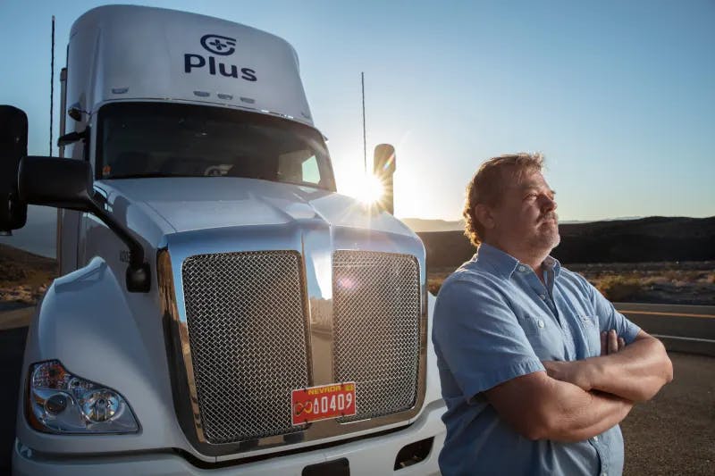 Truck driver standing near a Plus autonomous truck