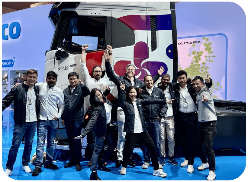Group of Plus employees celebrating in front of truck at a conference