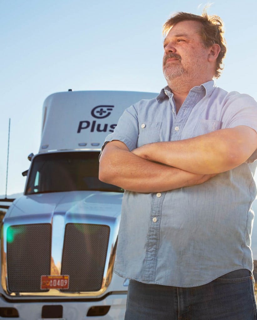 Man standing in front of autonomous Plus truck that is parked